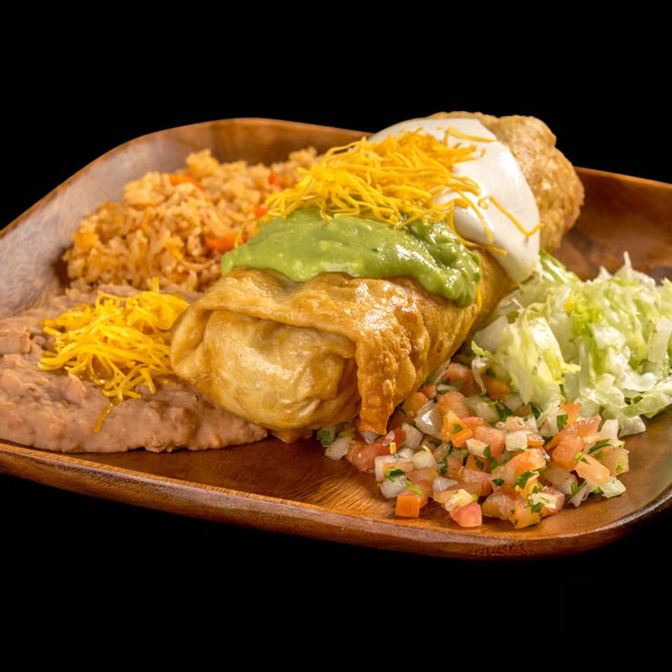 Golden-fried chimichanga topped with guacamole, sour cream, and shredded cheese, served with rice, beans, and pico de gallo.