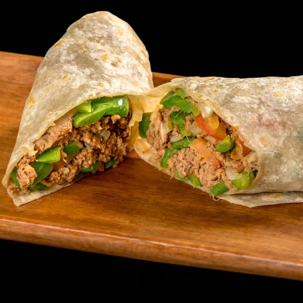 A large burrito, cut in half, revealing a filling of ground meat, green peppers, and onions.