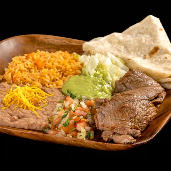 Carne asada plate with rice, refried beans, guacamole, pico de gallo, lettuce, and tortillas.